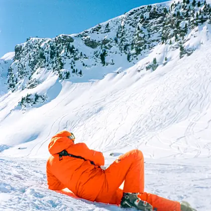 Figure in an orange suit lying on snow